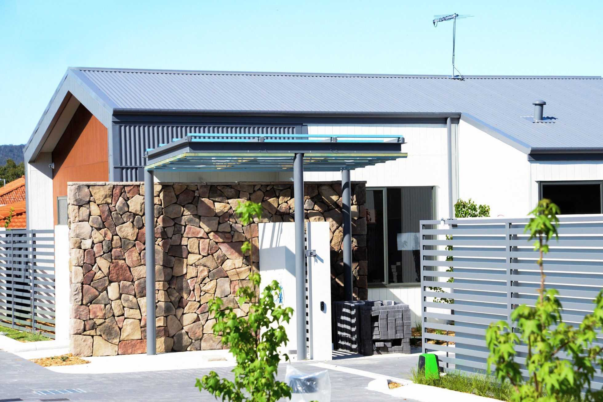 A exterior photograph showing a side view of the entrance to Grant Lewis Court. Highlighting the architectural detailing of the stone wall and façade of unit 1.